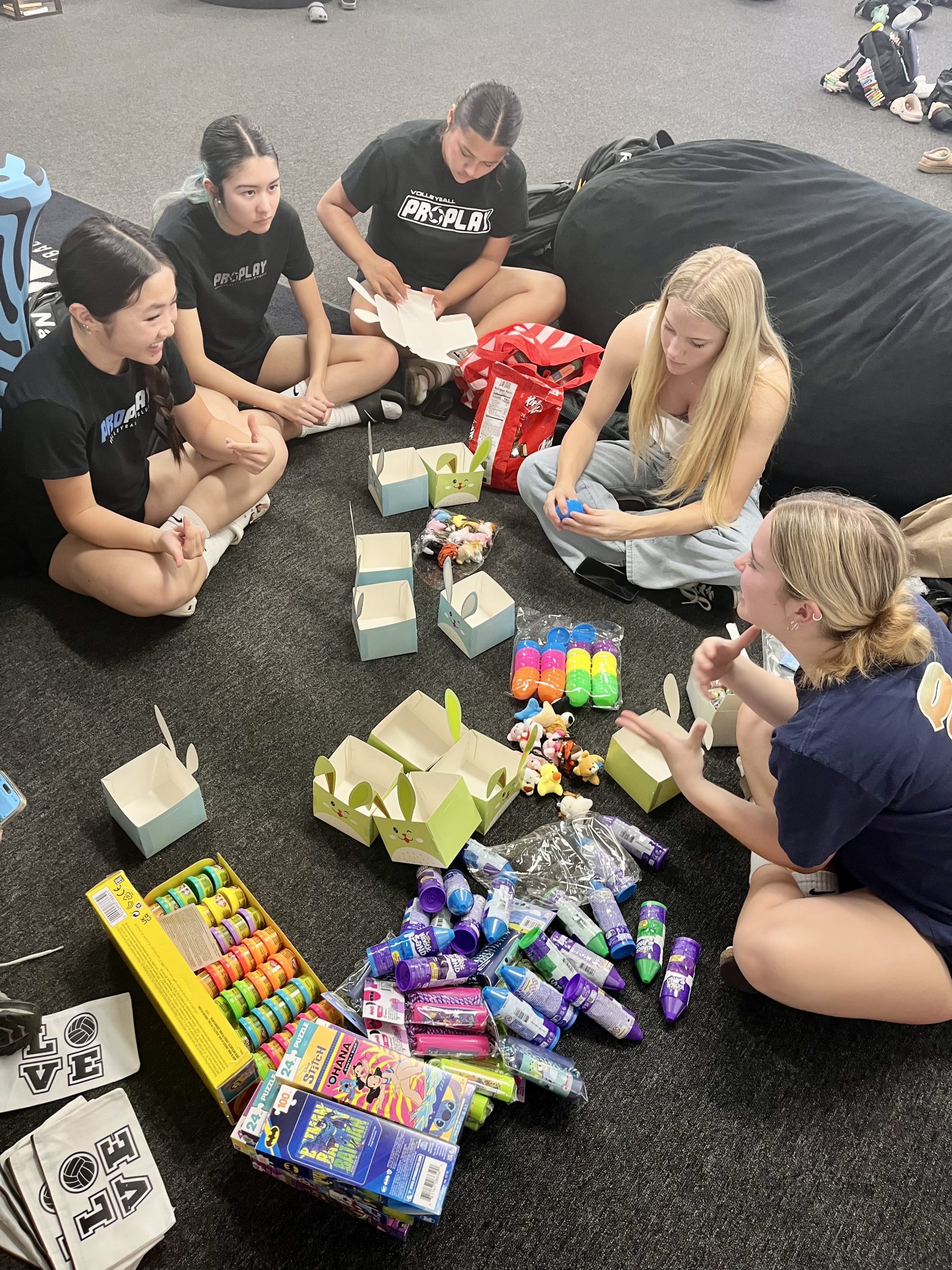 ProPlay Volleyball team members sitting on the floor and packaging Easter Baskets.