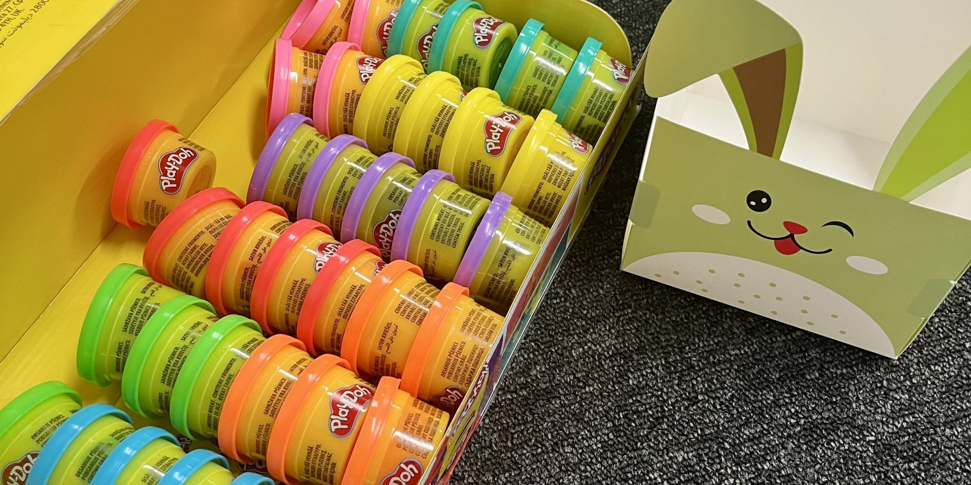 IMG_9638 A large pack of Play-Doh cans next to empty bunny cardboard Easter Baskets.